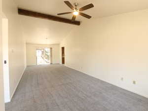 Empty room featuring vaulted ceiling with beams, ceiling fan, and carpet flooring