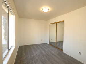 Unfurnished bedroom with dark carpet and a closet