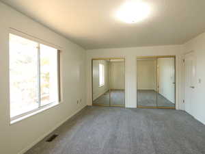 Unfurnished bedroom featuring two closets and carpet