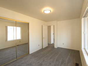 Unfurnished bedroom featuring dark carpet and a closet