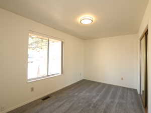 Unfurnished bedroom with dark carpet and a closet