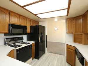 Kitchen featuring hanging light fixtures, light hardwood / wood-style floors, and black appliances