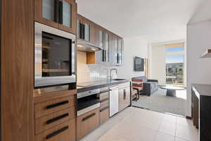 Kitchen with dishwashing machine, black cooktop, sink, wall oven, and light tile patterned floors