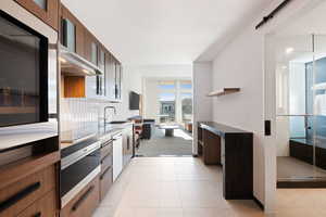 Kitchen featuring wall oven, black electric stovetop, light tile patterned floors, wall chimney range hood, and sink