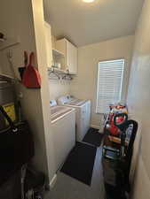 Clothes washing area with cabinets, dark carpet, and independent washer and dryer