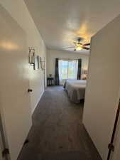 Carpeted bedroom with ceiling fan and a textured ceiling