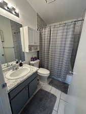 Full bathroom featuring vanity, a textured ceiling, shower / bath combination with curtain, and toilet