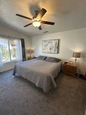 Bedroom with ceiling fan, lofted ceiling, carpet floors, and a textured ceiling