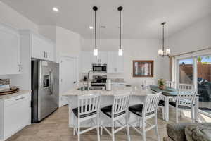 Kitchen with white cabinetry, sink, hanging light fixtures, and appliances with stainless steel finishes