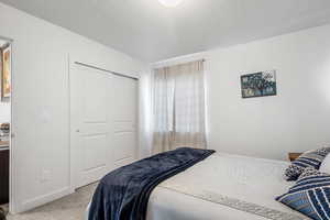 Carpeted bedroom featuring a textured ceiling and a closet