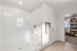 Bathroom with tile patterned flooring and a tile shower