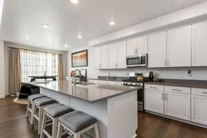 Kitchen with a kitchen bar, sink, white cabinetry, a center island with sink, and stainless steel appliances