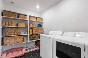 Laundry area featuring dark tile patterned flooring and washer and clothes dryer