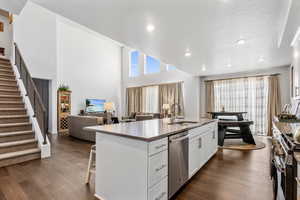 Kitchen featuring sink, white cabinetry, stainless steel appliances, dark hardwood / wood-style floors, and a center island with sink