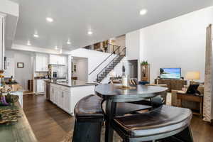 Kitchen featuring sink, white cabinetry, stainless steel appliances, dark hardwood / wood-style floors, and an island with sink