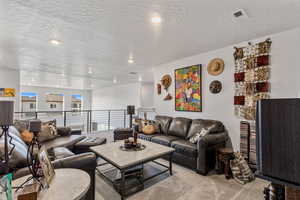 Carpeted living room featuring a textured ceiling