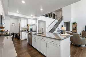 Kitchen featuring sink, appliances with stainless steel finishes, white cabinetry, dark hardwood / wood-style floors, and an island with sink