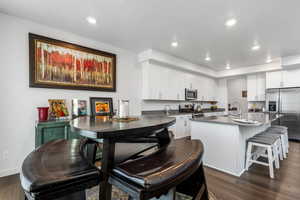 Kitchen with sink, stainless steel appliances, dark hardwood / wood-style floors, white cabinets, and a center island with sink