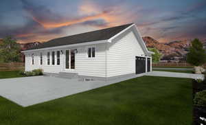 Back house at dusk with a yard, a mountain view, and a garage