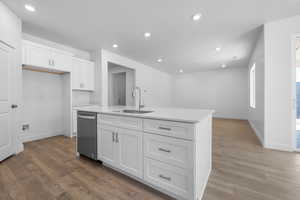 Kitchen with dark wood-type flooring, sink, white cabinetry, a center island with sink, and dishwasher