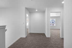 Hallway featuring dark colored carpet