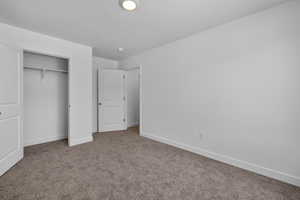 Unfurnished bedroom featuring carpet flooring, a closet, and a textured ceiling