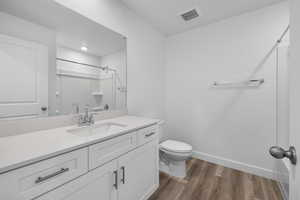 Bathroom featuring vanity, hardwood / wood-style flooring, and toilet