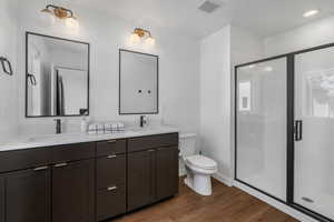 Bathroom featuring toilet, hardwood / wood-style floors, and a shower with shower door