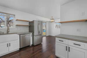 Kitchen with tasteful backsplash, sink, white cabinets, and appliances with stainless steel finishes