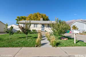 Ranch-style home featuring a mountain view and a front lawn