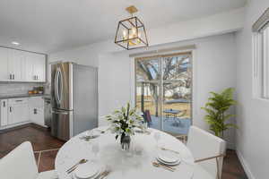 Dining area with dark wood-type flooring and a notable chandelier