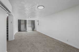 Carpeted spare room featuring a textured ceiling