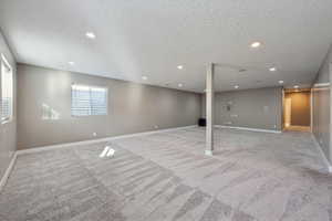 Basement featuring light carpet and a textured ceiling