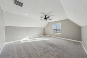 Bonus room with ceiling fan, carpet floors, a textured ceiling, and vaulted ceiling