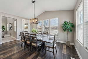 Dining space with lofted ceiling, dark hardwood / wood-style floors, and a chandelier