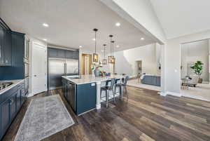 Kitchen featuring a spacious island, sink, a breakfast bar area, decorative light fixtures, and appliances with stainless steel finishes