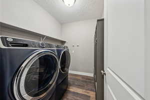 Clothes washing area featuring washing machine and dryer, dark hardwood / wood-style floors, and a textured ceiling