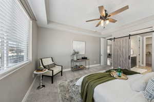 Carpeted bedroom featuring a textured ceiling, a barn door, and a raised ceiling