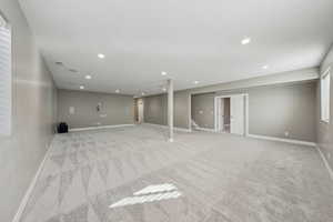 Basement with light colored carpet and a textured ceiling