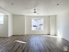 Empty room with ceiling fan, a textured ceiling, and dark hardwood / wood-style flooring