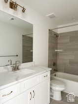 Full bathroom with tiled shower / bath combo, vanity, tile patterned flooring, and toilet