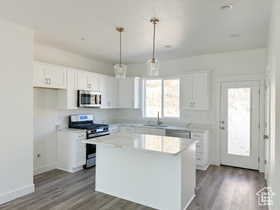 Kitchen with a kitchen island, white cabinetry, appliances with stainless steel finishes, and decorative light fixtures