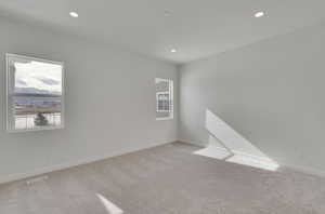 Empty room featuring light carpet, baseboards, visible vents, and recessed lighting