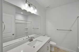 Full bath with visible vents, baseboards, toilet,  shower combination, and vanity