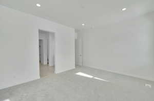 Spare room with baseboards, recessed lighting, and light colored carpet