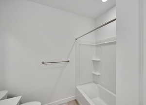 Full bathroom with toilet, shower / tub combination, and baseboards