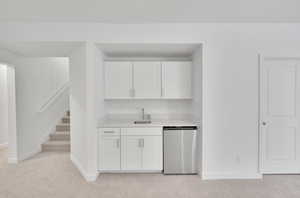 Kitchen featuring light carpet, white cabinetry, light countertops, and dishwasher