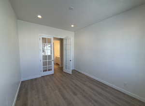 Unfurnished bedroom with french doors and dark wood-type flooring