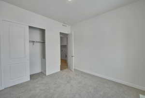 Unfurnished bedroom with a closet, light carpet, visible vents, and baseboards