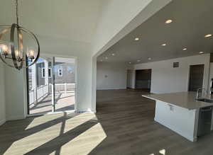 Interior space featuring sink, a kitchen island with sink, a notable chandelier, dark hardwood / wood-style flooring, and stainless steel dishwasher